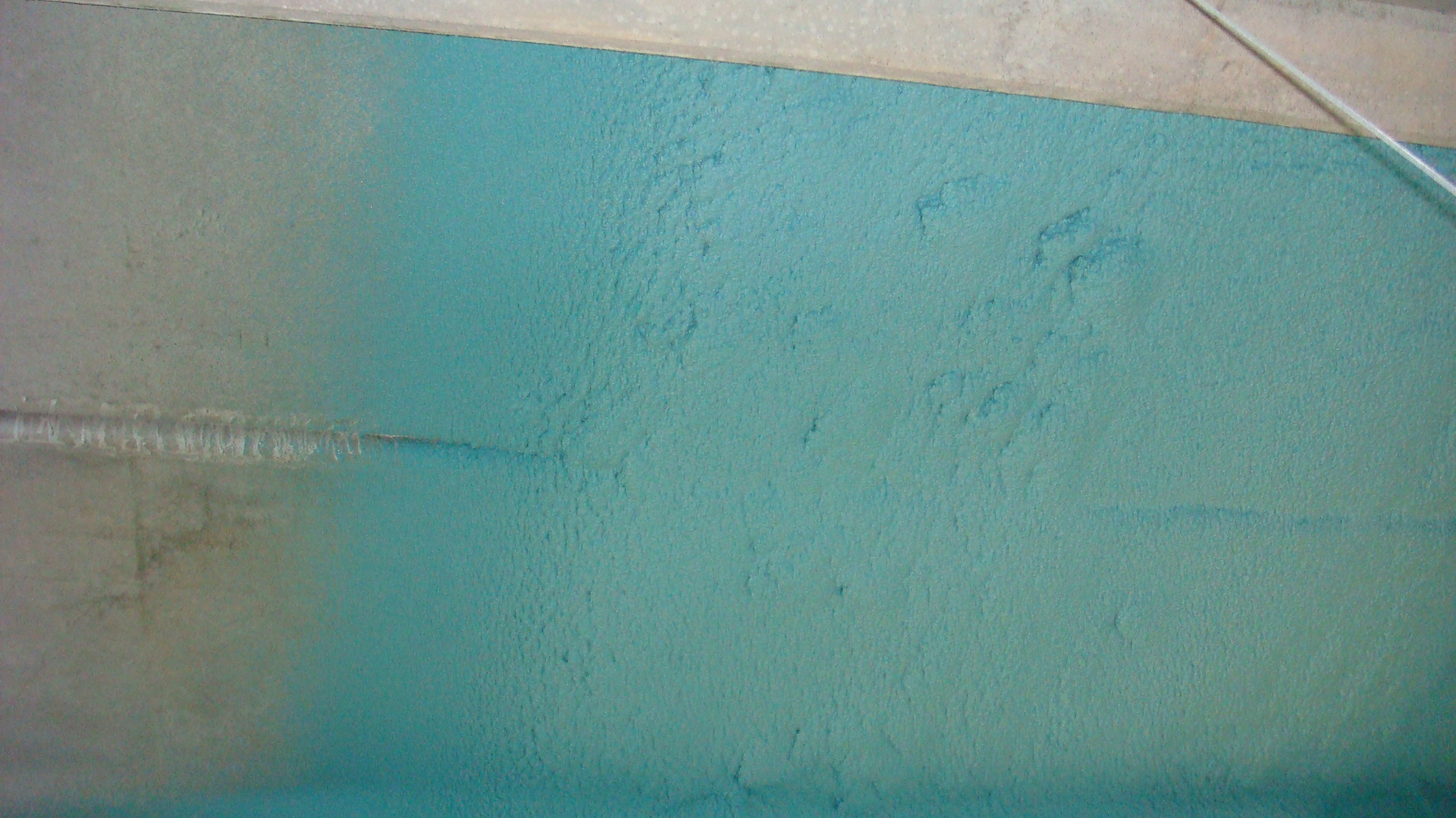 Applicator spraying polyurea membrane on industrial metal decking