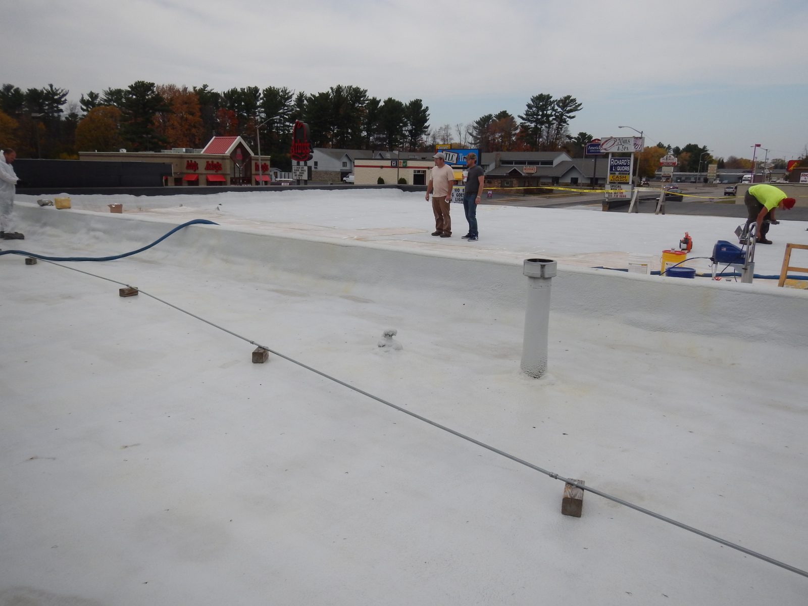 Corrugated metal deck being coated with a seamless polyurea membrane