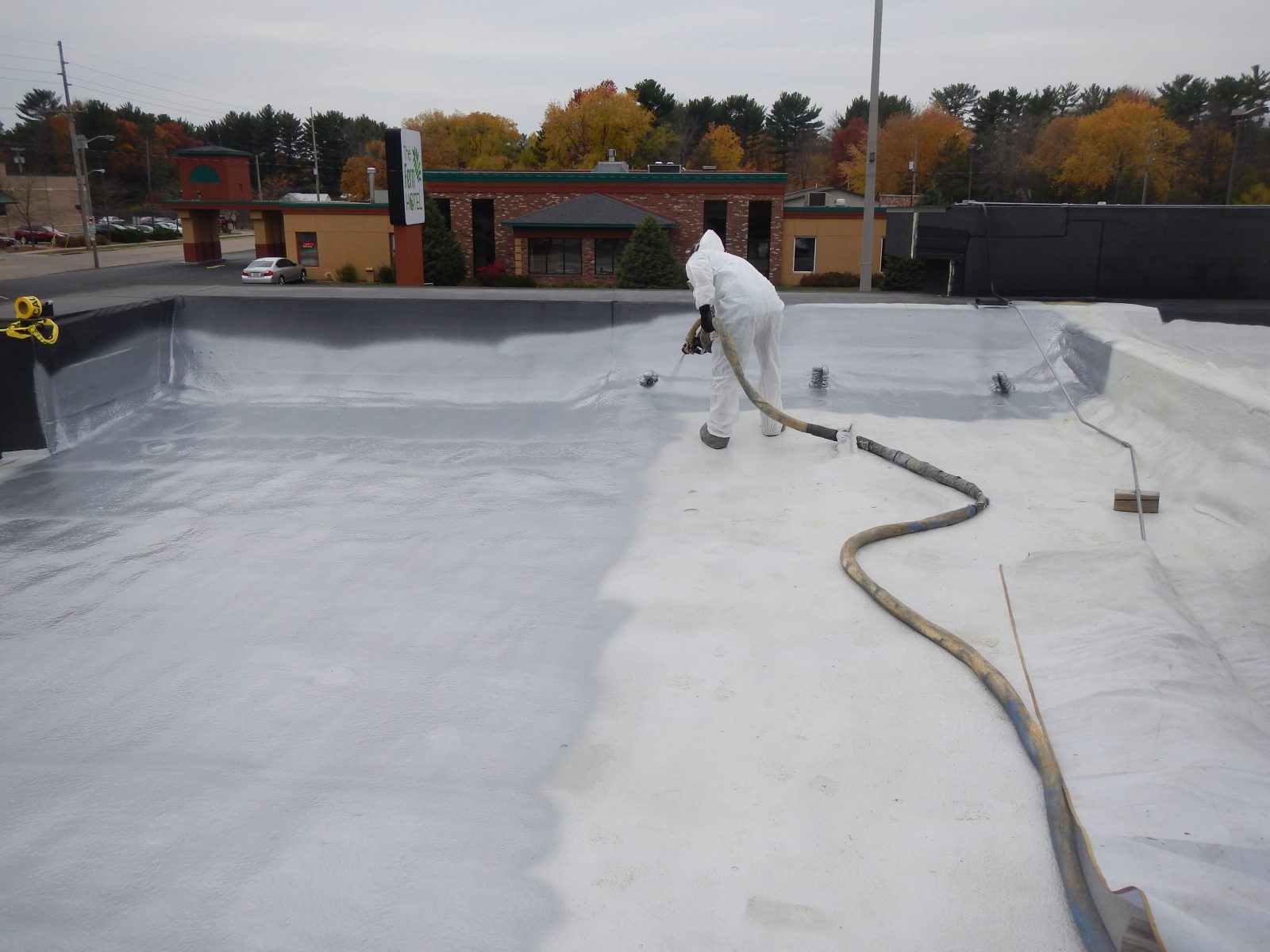 Corrugated deck panel with sprayed coating over laps and fasteners